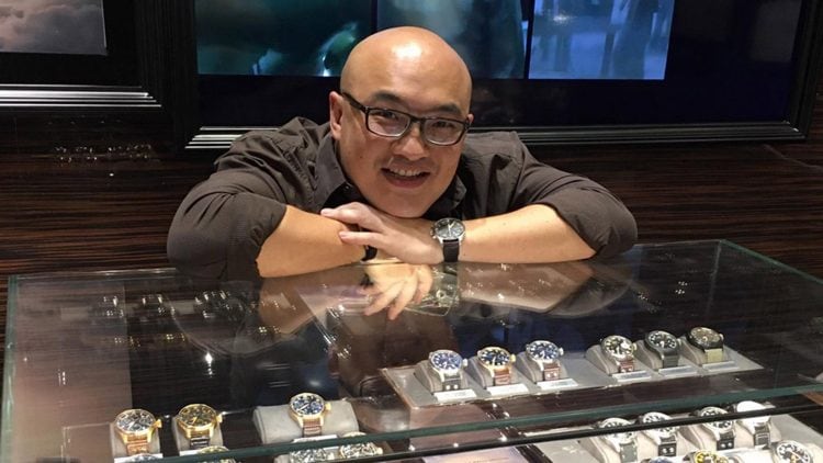 Erwin Chu leaning on a glass display case that contains watch collections from IWC.