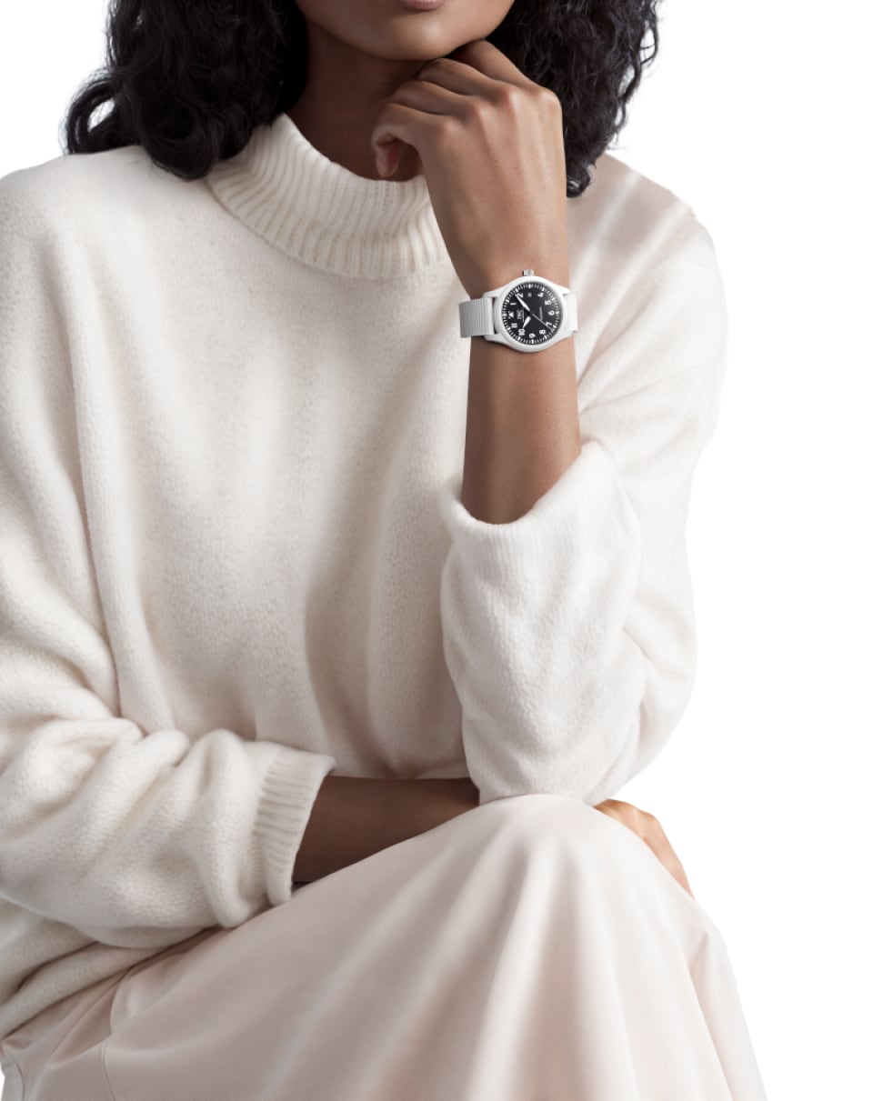 A woman with a white outifit wearing the Pilot’s Watch Automatic 41 TOP GUN Lake Tahoe with white case and strap, and black dial