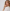 L’ambassadrice de la marque IWC Gisele Bündchen en chemise blanche portant la montre IW503701 Portugieser Calendrier Perpétuel 44 avec un cadran argenté, un boîtier en Armor Gold® 18 carats et un bracelet en cuir brun foncé.