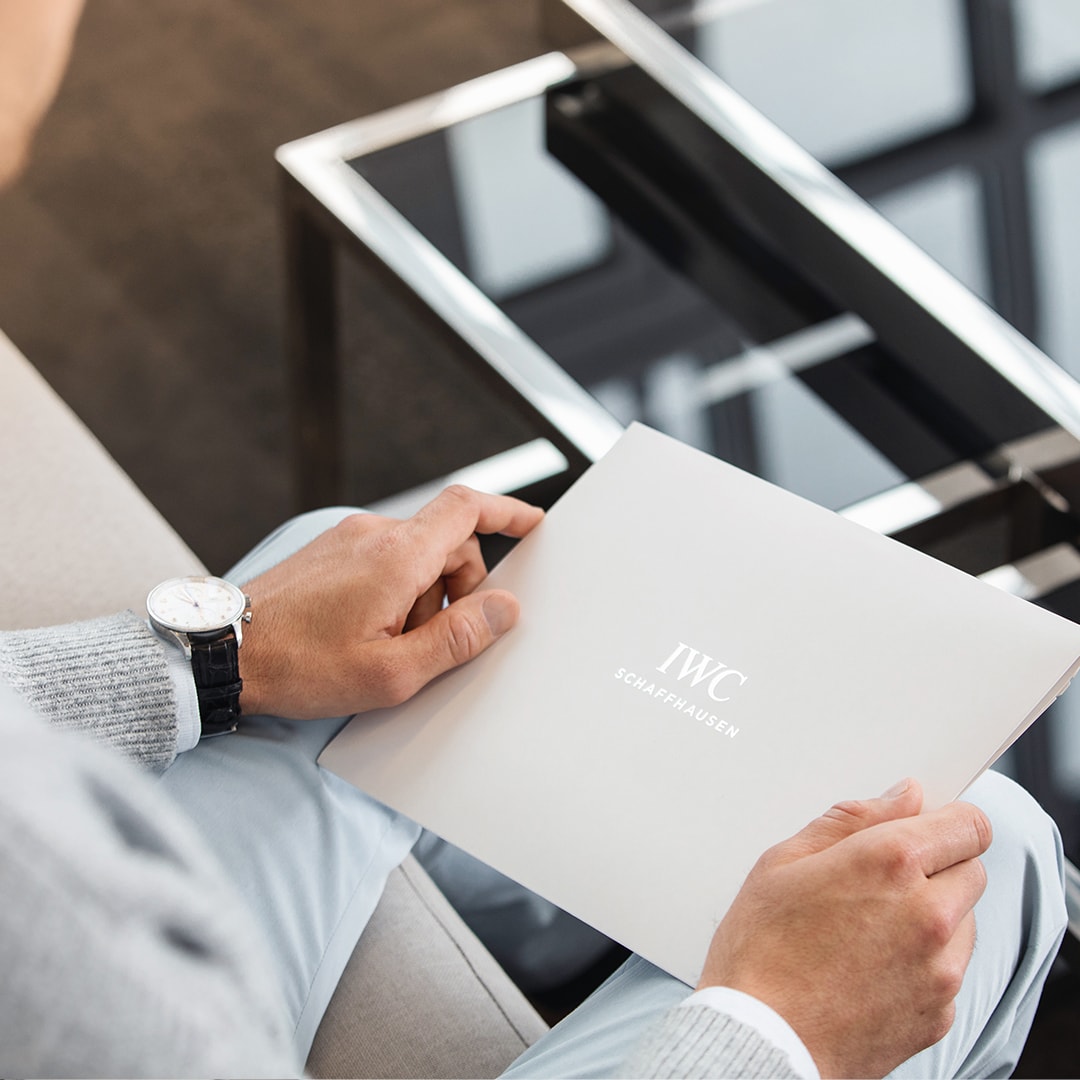 Person holding an envelope with 'IWC Schaffhausen' written on it