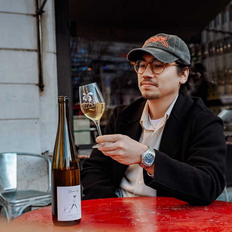 Pascal Grob sitting outside the Marius wine bar in Geneva with a white wine and wearing an IWC watch