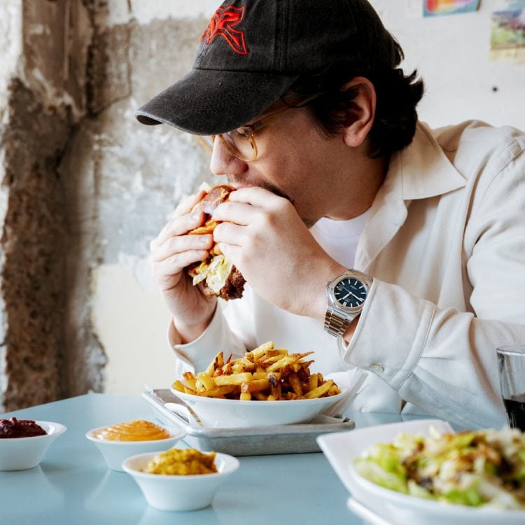 Pascal Grob biting into a burger wearing an IWC watch.